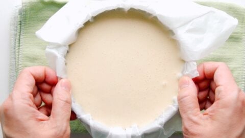 Removing bubbles from the cheesecake batter by dropping the pan on a flat surface.