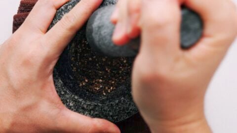 Cracking black peppercorns with a mortar and pestle.