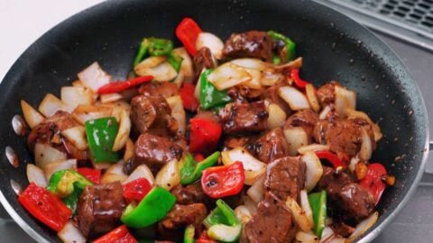 Stir-frying onions and peppers with marinated beef.