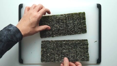 Cutting sheet of nori in half.