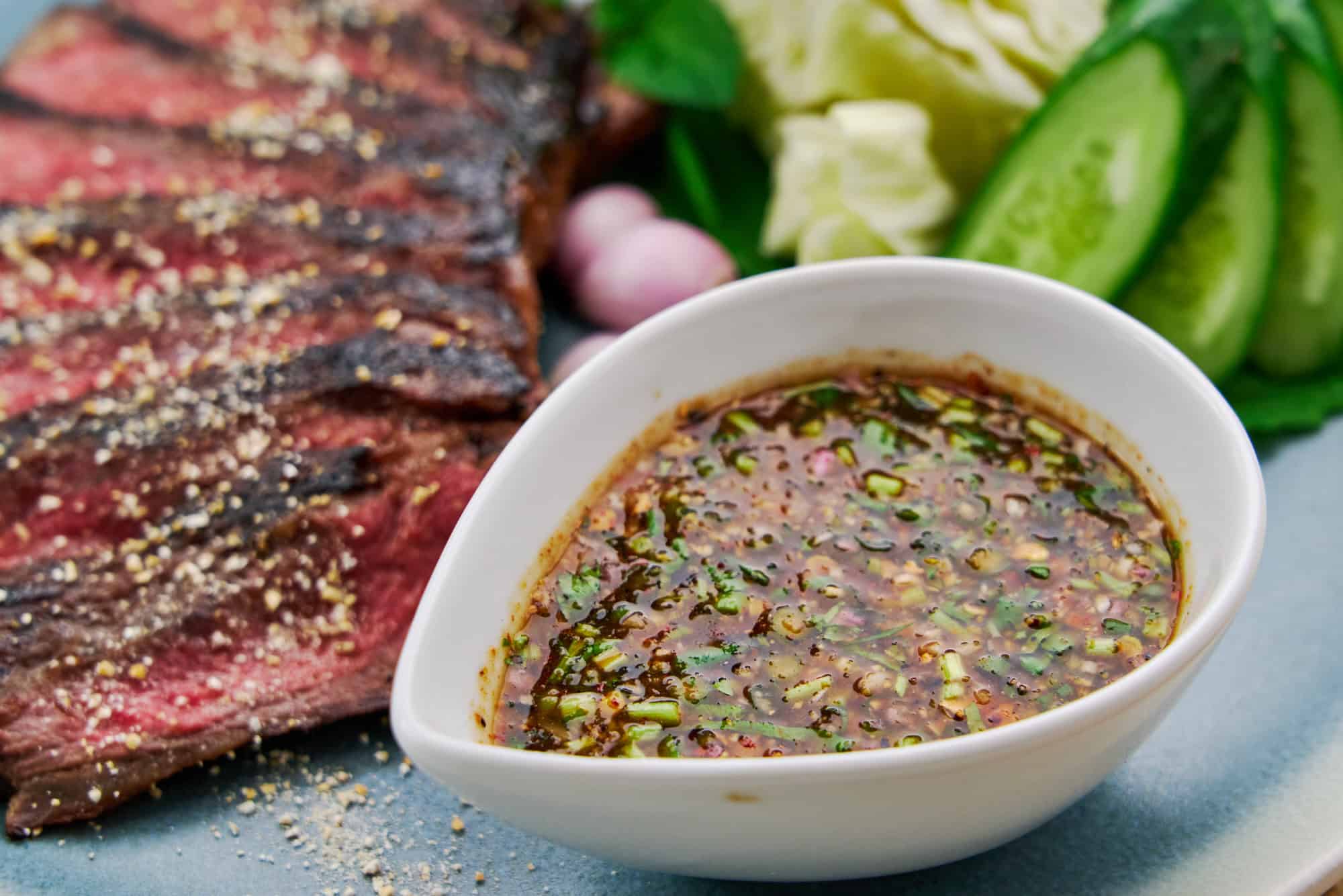 Close-up of a bowl of Nam Jim Jaew, a vibrant Thai bbq sauce served with Crying Tiger Beef.