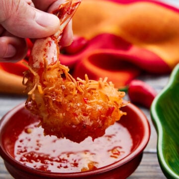 Dipping coconut fried shrimp in a orange chili sauce.
