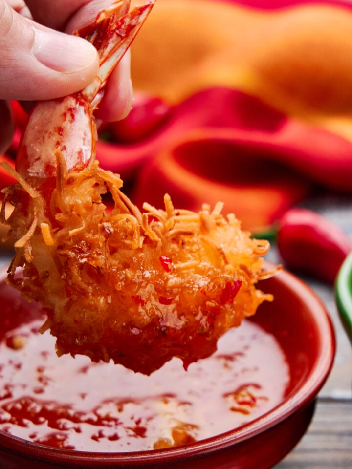 Dipping coconut fried shrimp in a orange chili sauce.