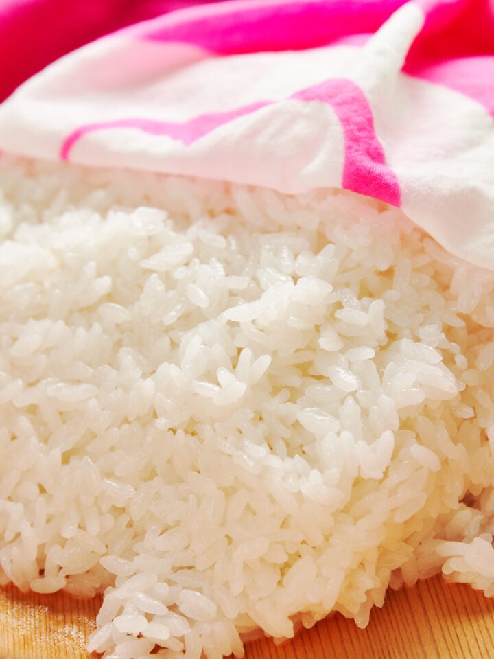 Sushi rice covered in a damp pink dishcloth to prevent it from getting dried out.