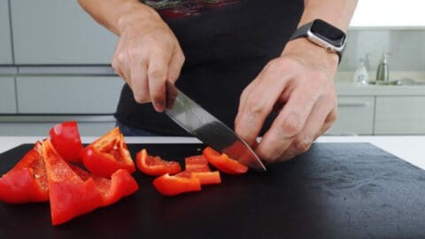 Cutting red peppers on a black cutting board.