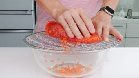 Separating salmon eggs from from roe sack using a mesh grill.