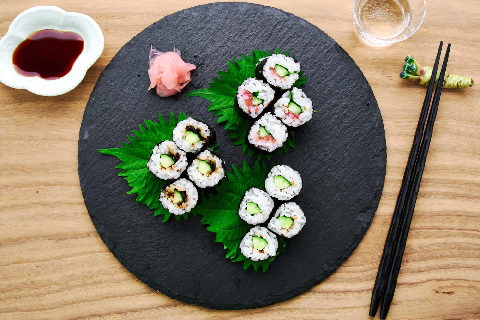 Overhead view of colorful Kappa Maki sushi rolls, showcasing the vibrant green cucumber core against a contrasting backdrop of white sushi rice and black nori.