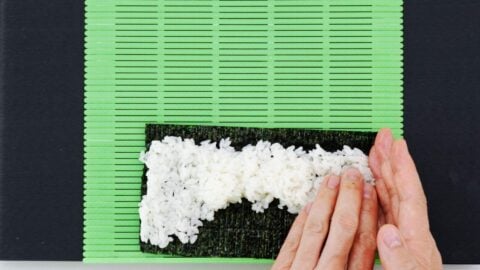Spreading sushi rice on a nori sheet.