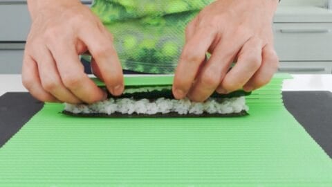Rolling Kappa Maki sushi rolls with a sushi mat.