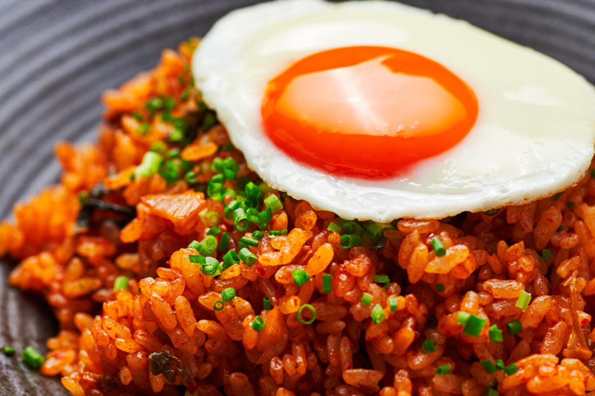 Sunny-side-up egg on top of a bowl of spicy kimchi fried rice, or kimchi bokkeumbap.