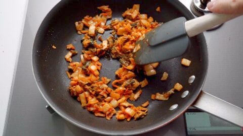 Sauteeing kimchi in a frying pan for kimchi fried rice.