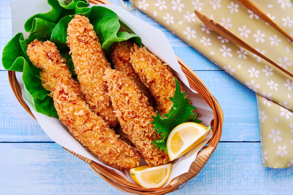 Japanese crispy fried chicken tenders served in a basket with lettuce and lemon wedges.
