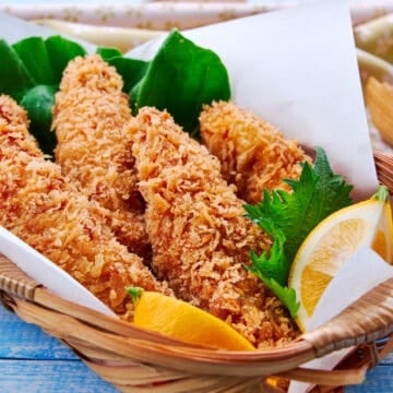 Crispy panko chicken tenders served with lemon wedges and lettuce in a basket.