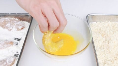 Dipping flour coated chicken tenders in egg.