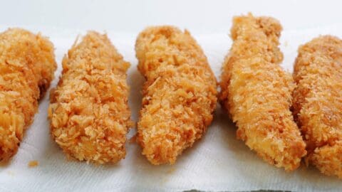 Draining panko crusted chicken tenders on a paper towels.