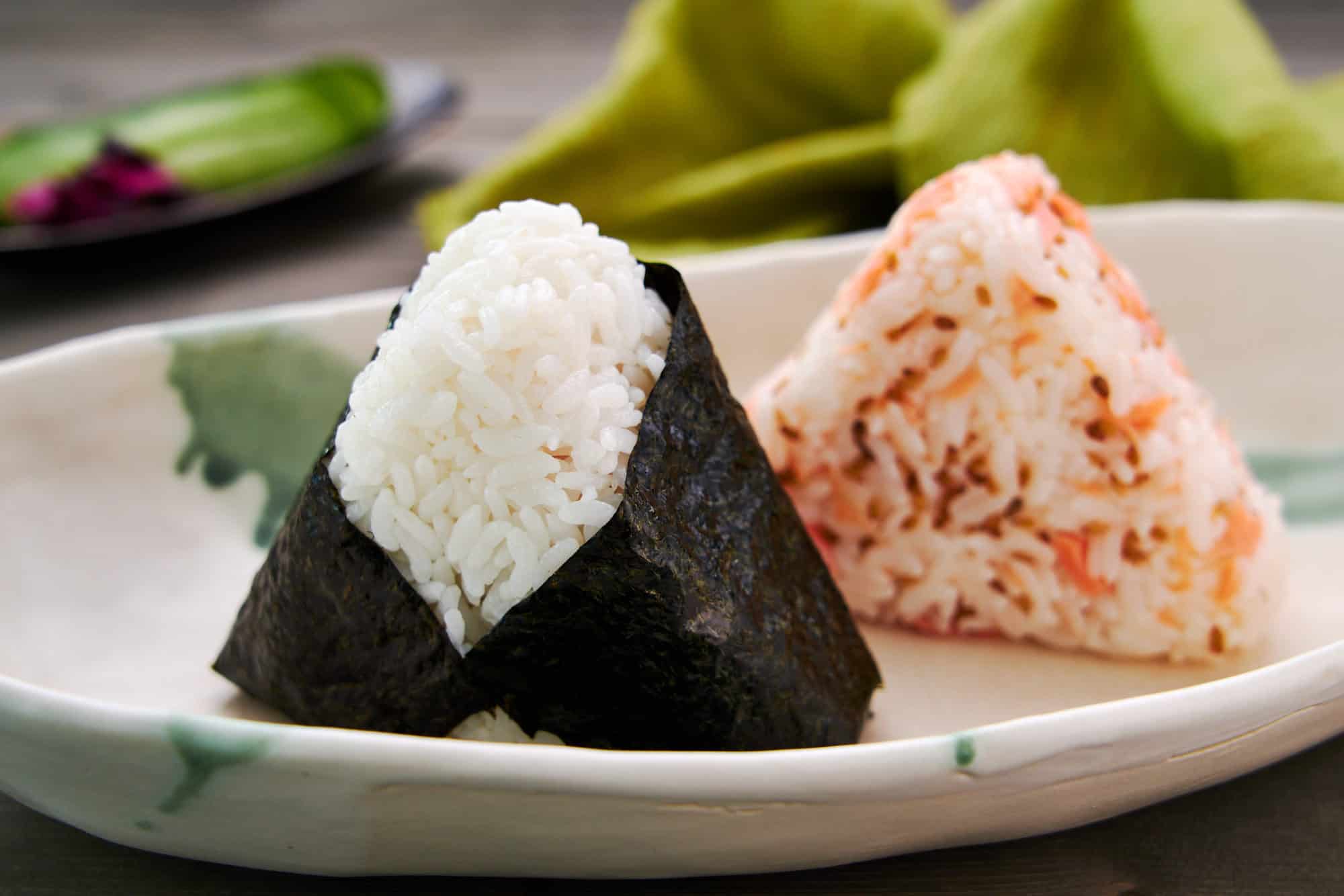 Japanese salted salmon onigiri or rice balls. One filled with salmon flakes and the other mixed with salmon.