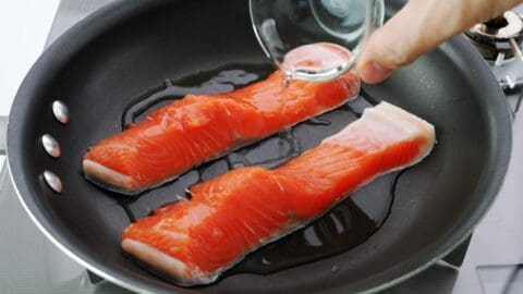 Cured salmon in frying pan with sake.