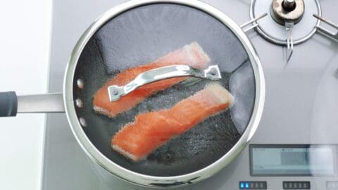 Steaming cured salmon in a frying pan with a lid.
