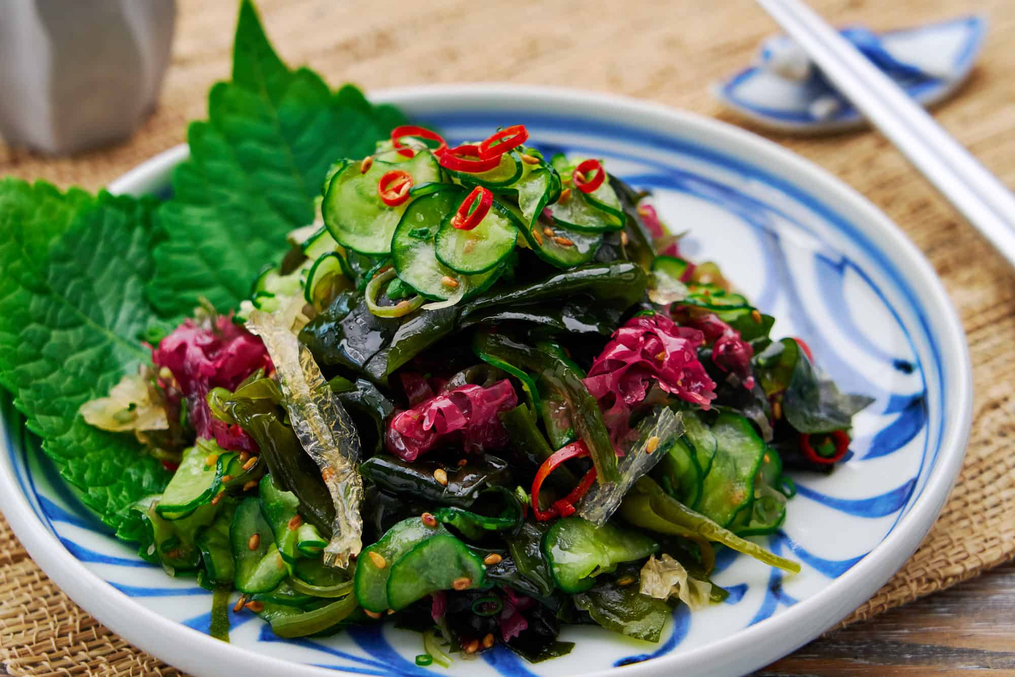 A mouthwatering plate of Japanese seaweed salad with a mix of wakame, konbu, agar, and other seaweed, along with crispy cucumbers and a nutty sesame dressing.