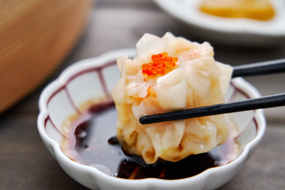 Dipping shumai (steamed shrimp and pork dumplings) in black vinegar and ginger sauce.