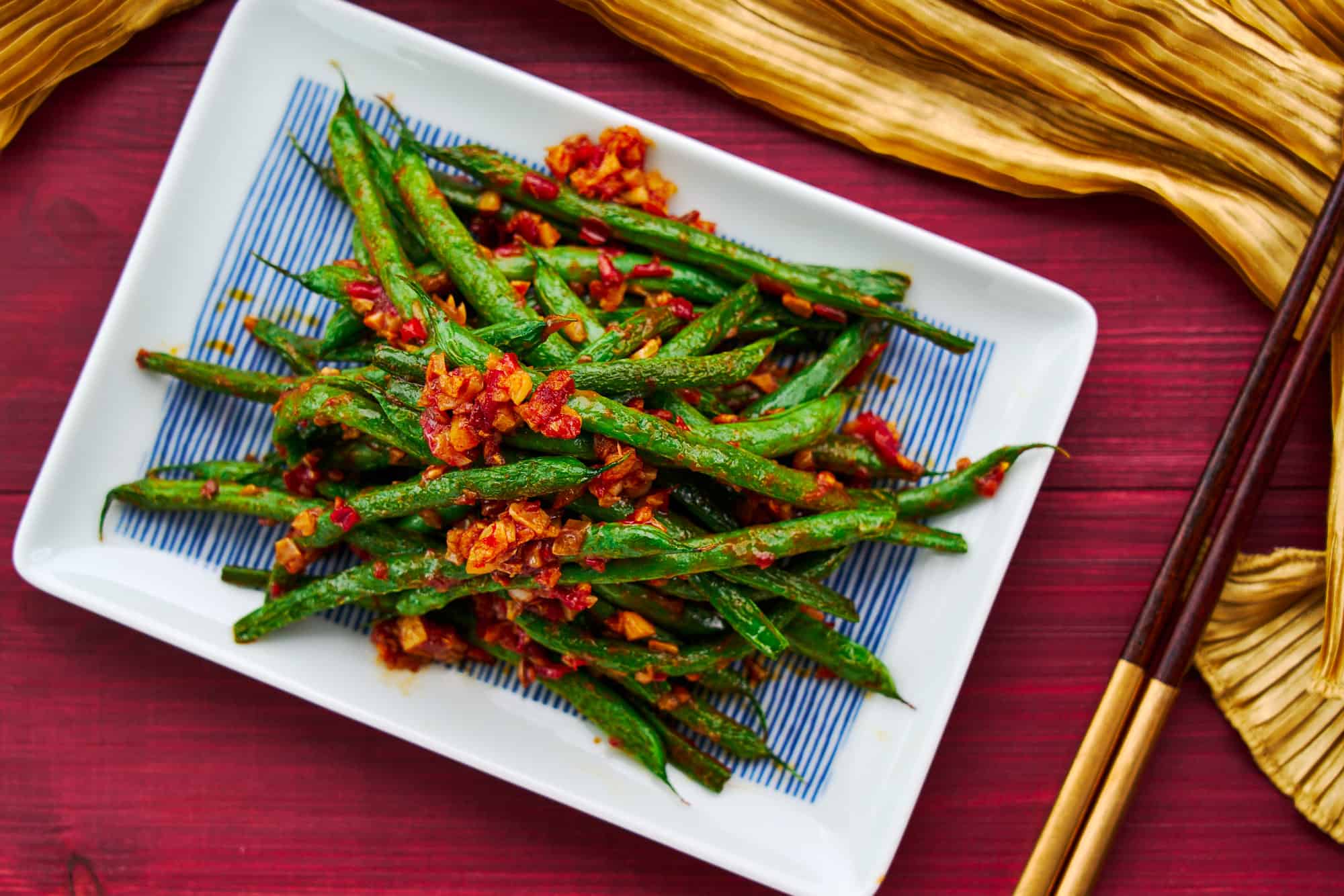 A plate of tender green beans stir-fried with chili paste and garlic. An easy vegan Chinese recipe.