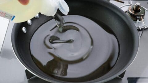 Adding oil to a frying pan.