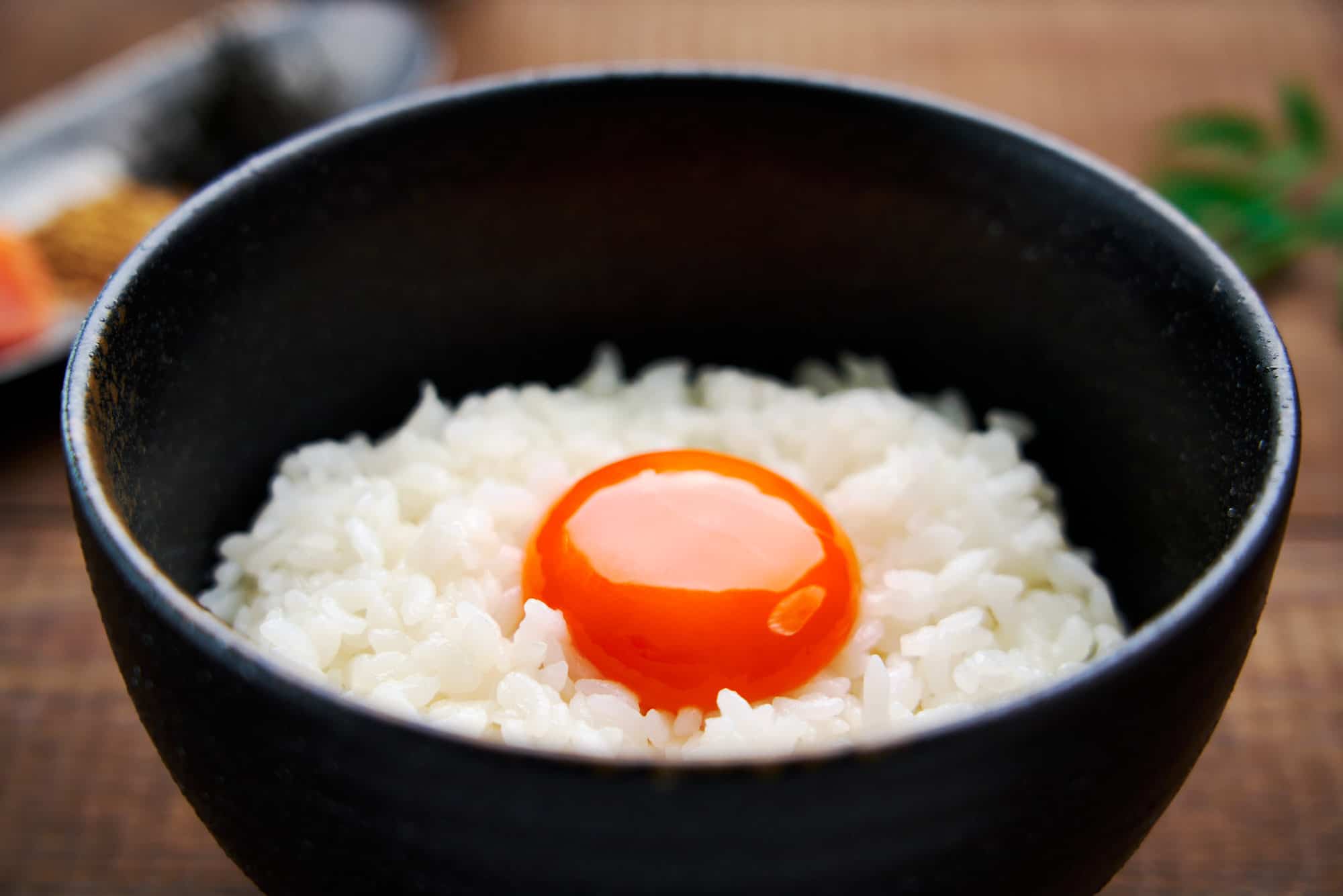 Close-up side view of Tamago Gohan, capturing the beautiful texture contrast between the raw golden egg yolk and the cooked rice grains.